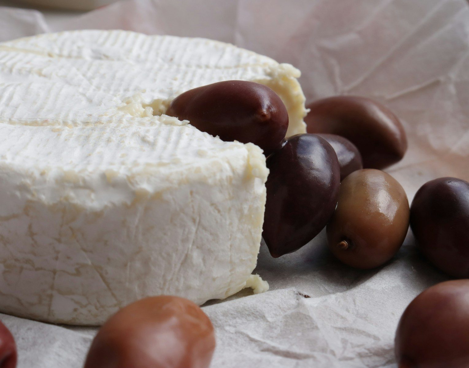 Cheese wheel with olives on parchment paper