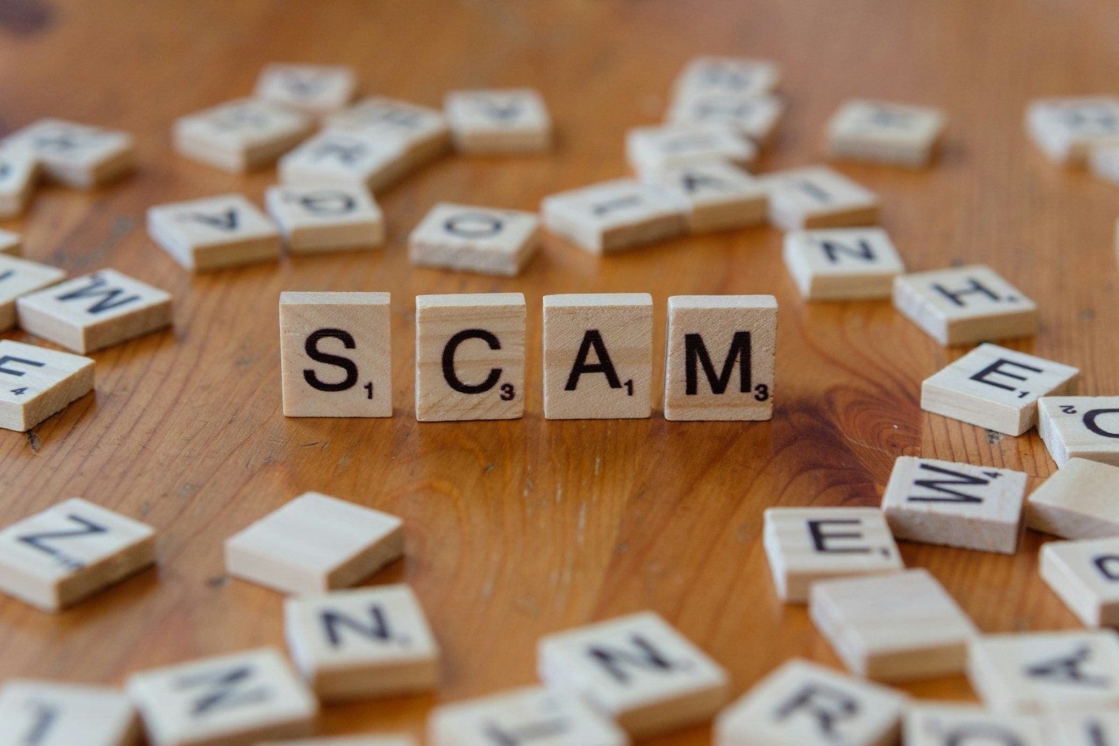 Scam spelled with scrabbles on a wooden table